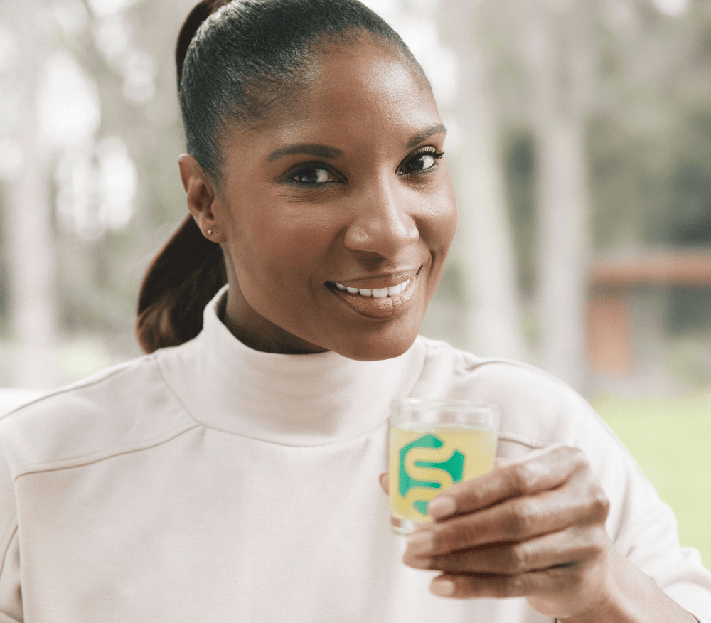 A head shot of Denise Lewis holding her shot of Symprove