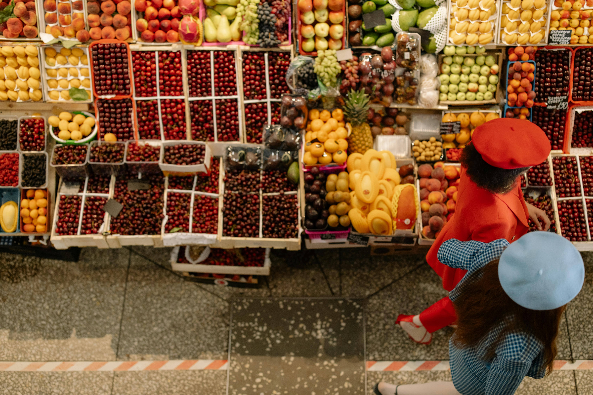 Two people walking past an autumnal fruit stand
