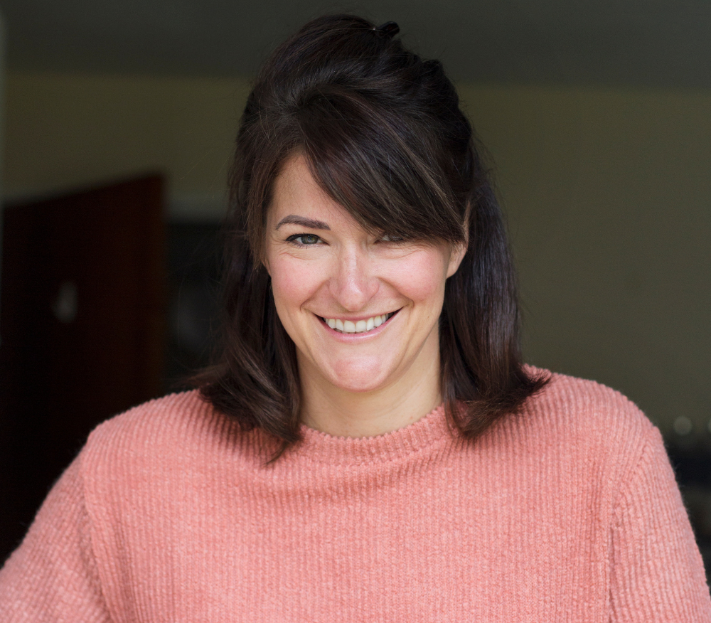 Dietitian Laura Tilt smiling at the camera while carrying a basket of veg