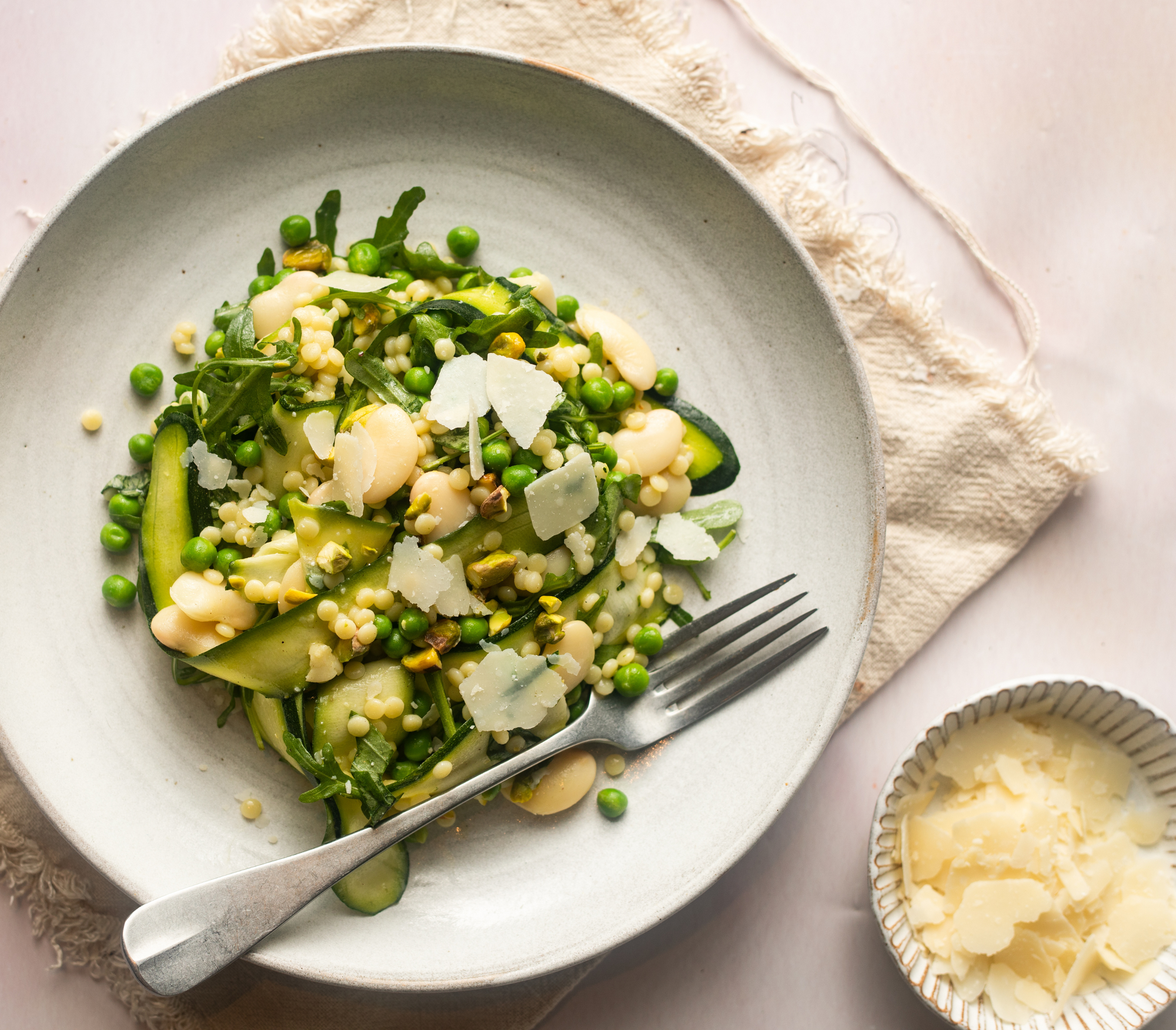Gut loving grain bowl with butterbeans, courgette, garden peas, pistachios, rocket and cous-cous