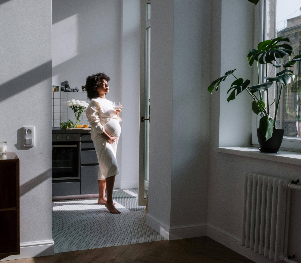 A-pregnant-figure-basking-in-morning-sunlight-with a-glass-in-hand