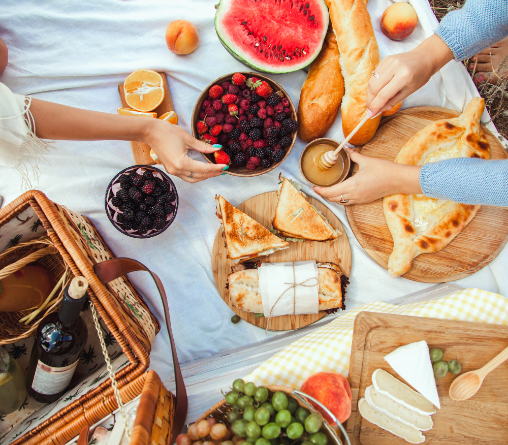 Friends having a picnic outside with fruit, cheese, biscuits, bread and wine