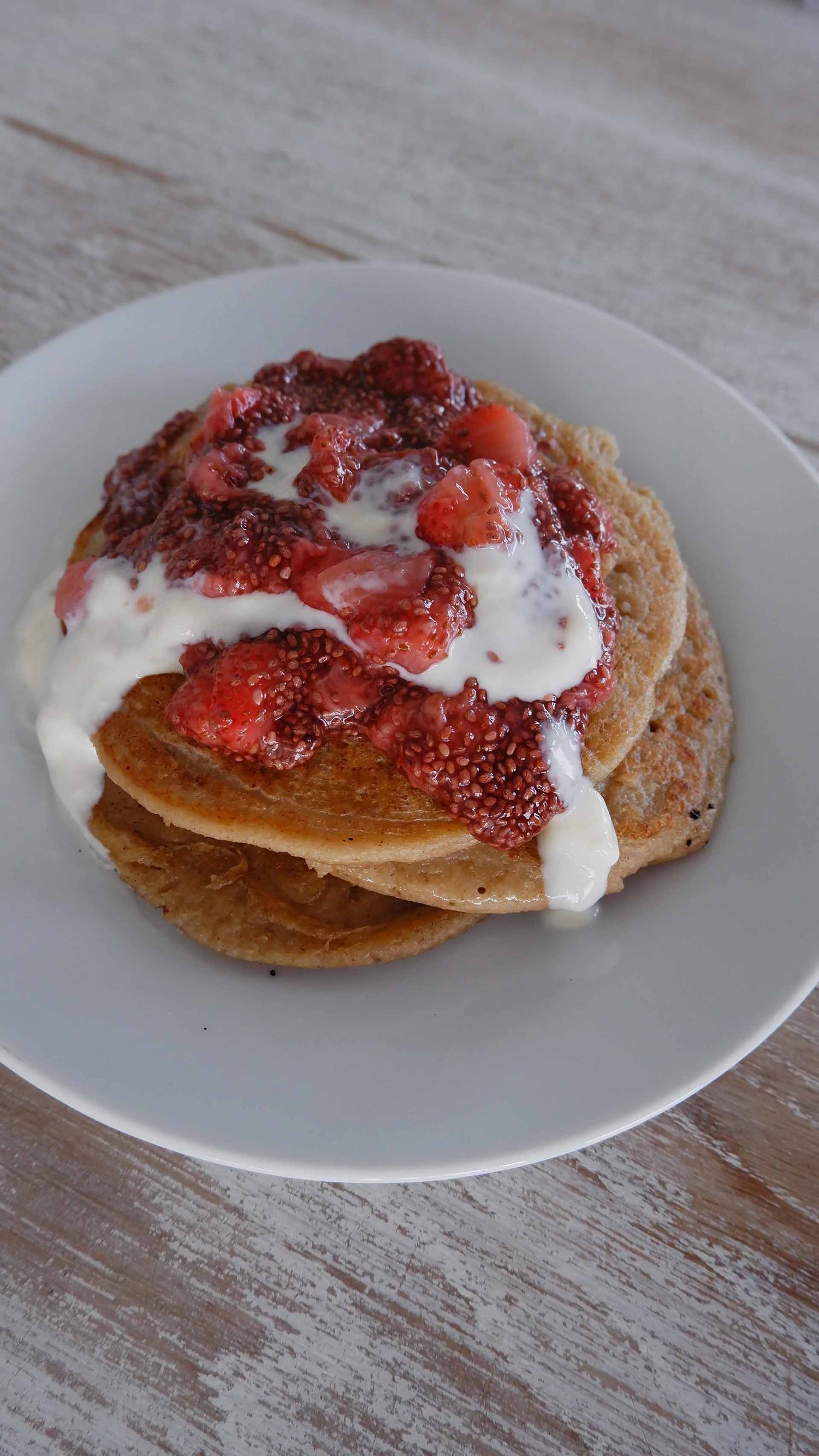 Oat pancakes covered in strawberries and coconut yoghurt.