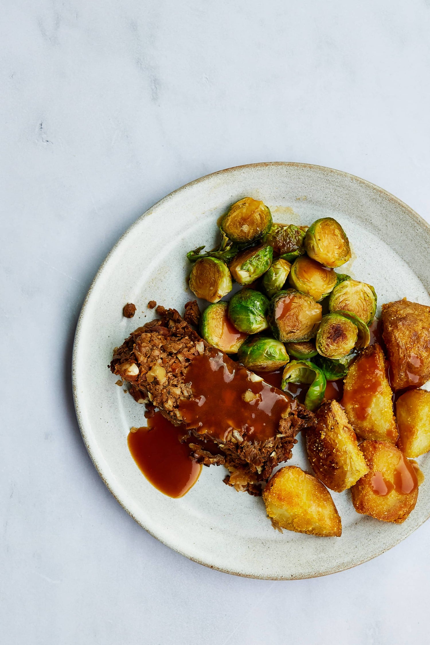 Christmas dinner with roast potatoes, mushroom nut roast and brussels sprouts on a white dinner plate