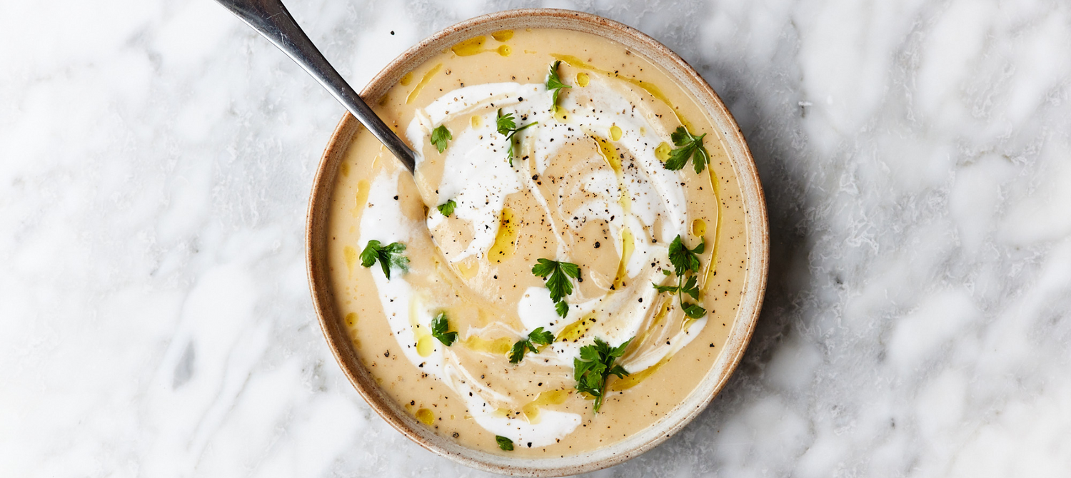 Roasted cauliflower soup with some dressing on a white countertop