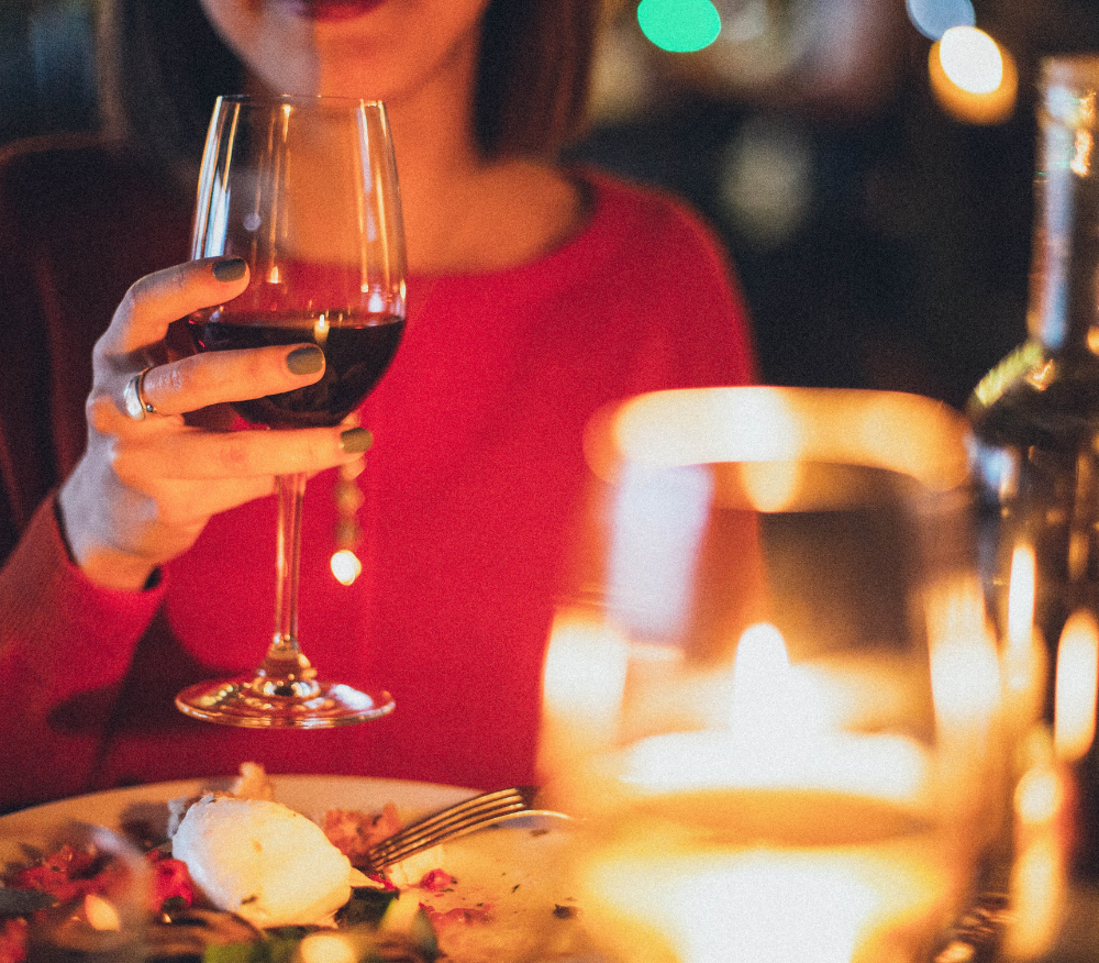 Lady in red jumper holds a glass of red wine up