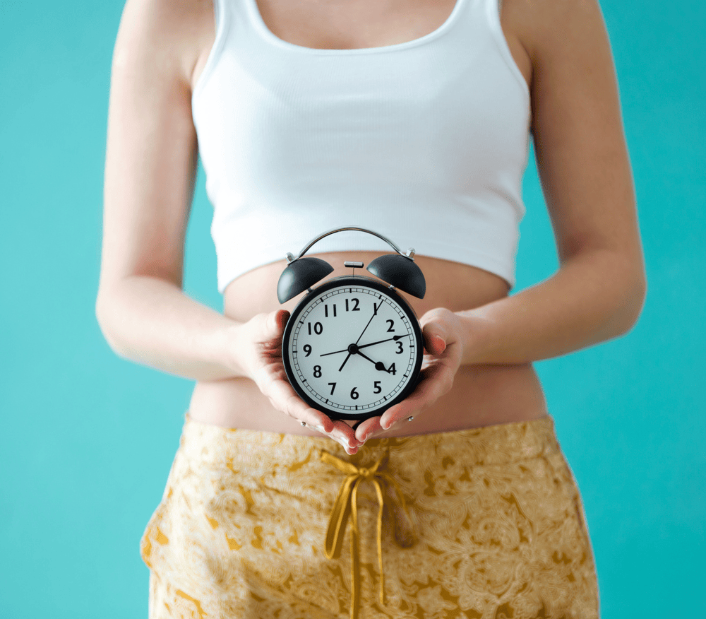 Lady holding a clock in front of her gut
