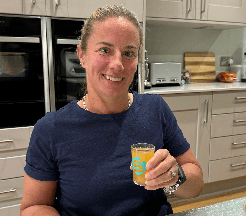 Lucy Shuker holding a shot glass of Symprove
