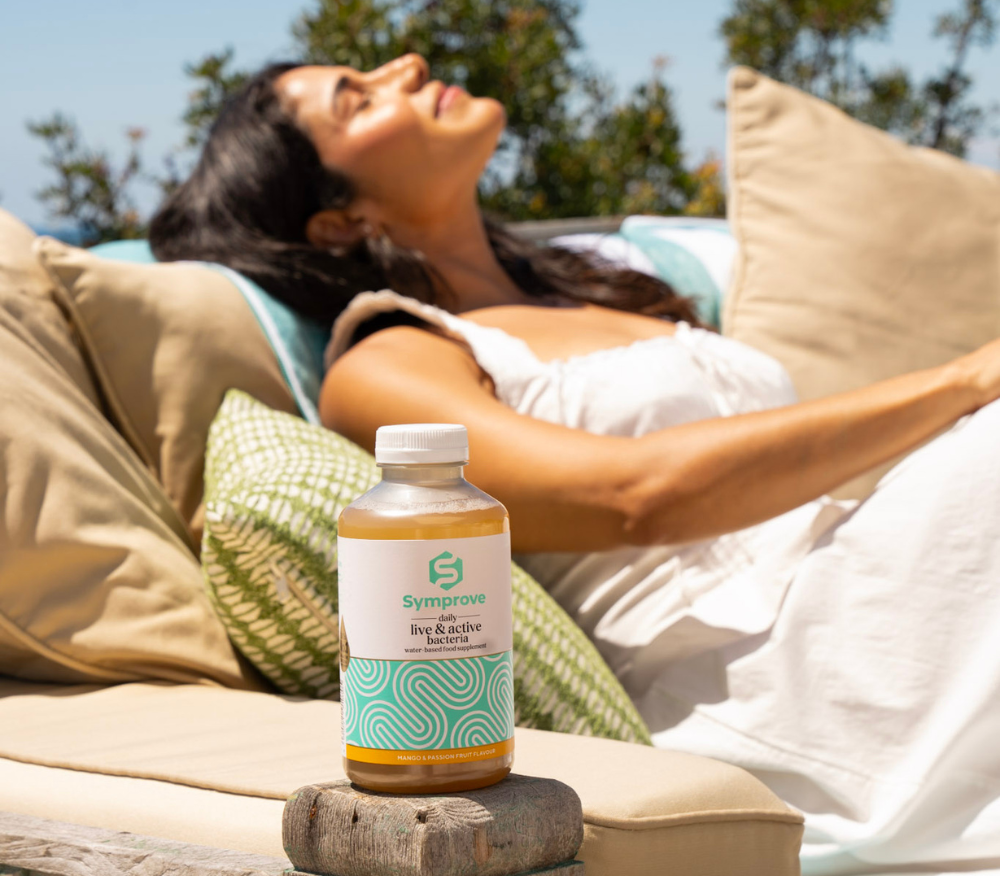 Lady sitting in the sun with a bottle of Symprove